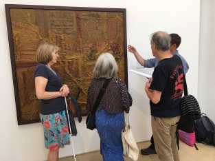Four people stand in front of a large abstract painting